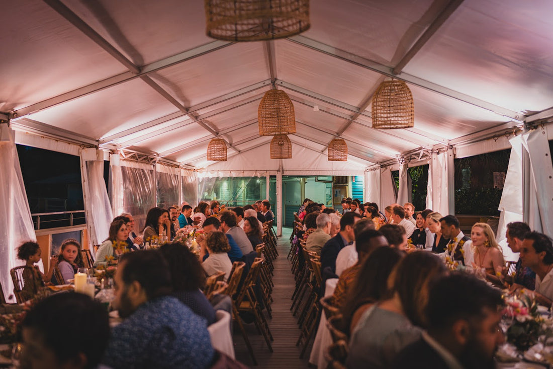 Indoor tent decorated beautifully filled with people attending a wedding drinking and celebrating a wedding.
